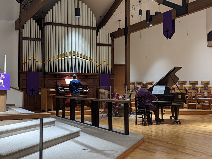 Wyatt Smith sitting playing organ while Sheila Bristow is playing piano in a church