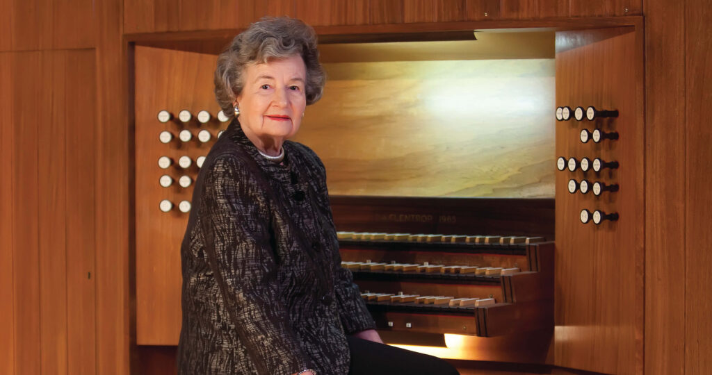 A woman sits on the bench of a 3-manual tracker organ