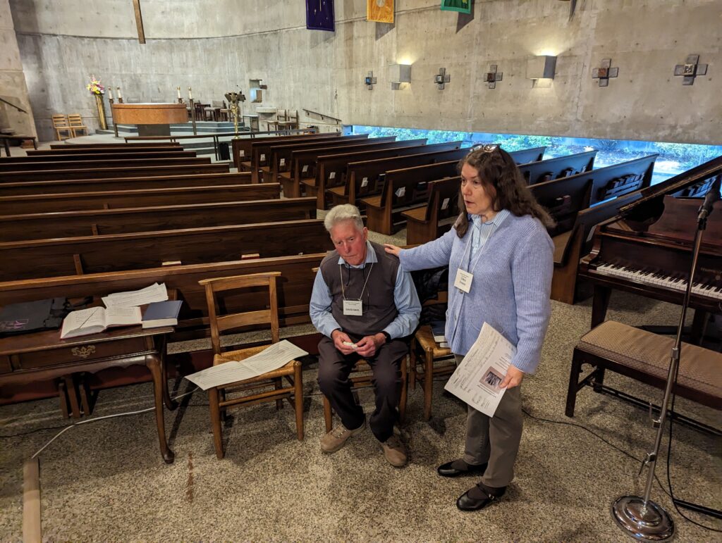 woman standing beside seated man with her hand on his shoulder