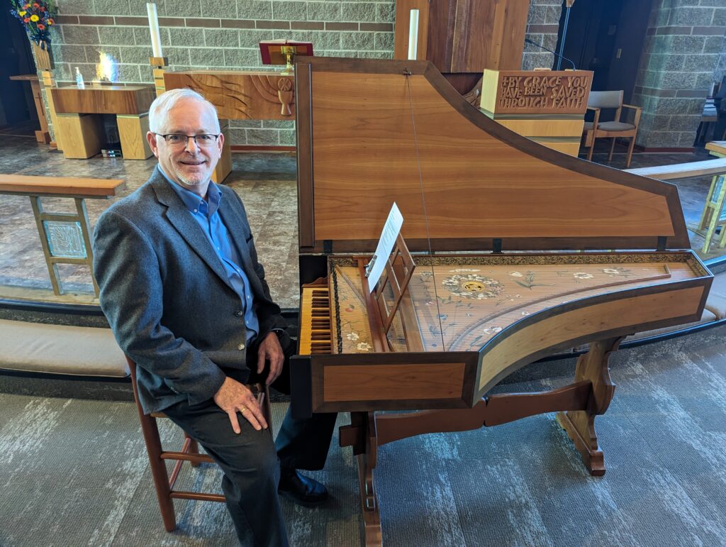 man sitting on chair in front of harpsichord